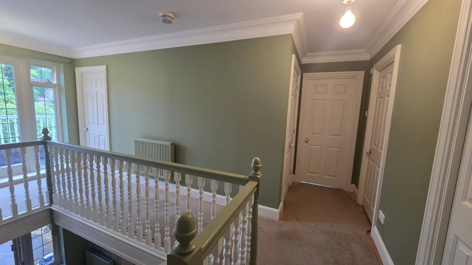 Landing after: repainted in sage green with white woodwork