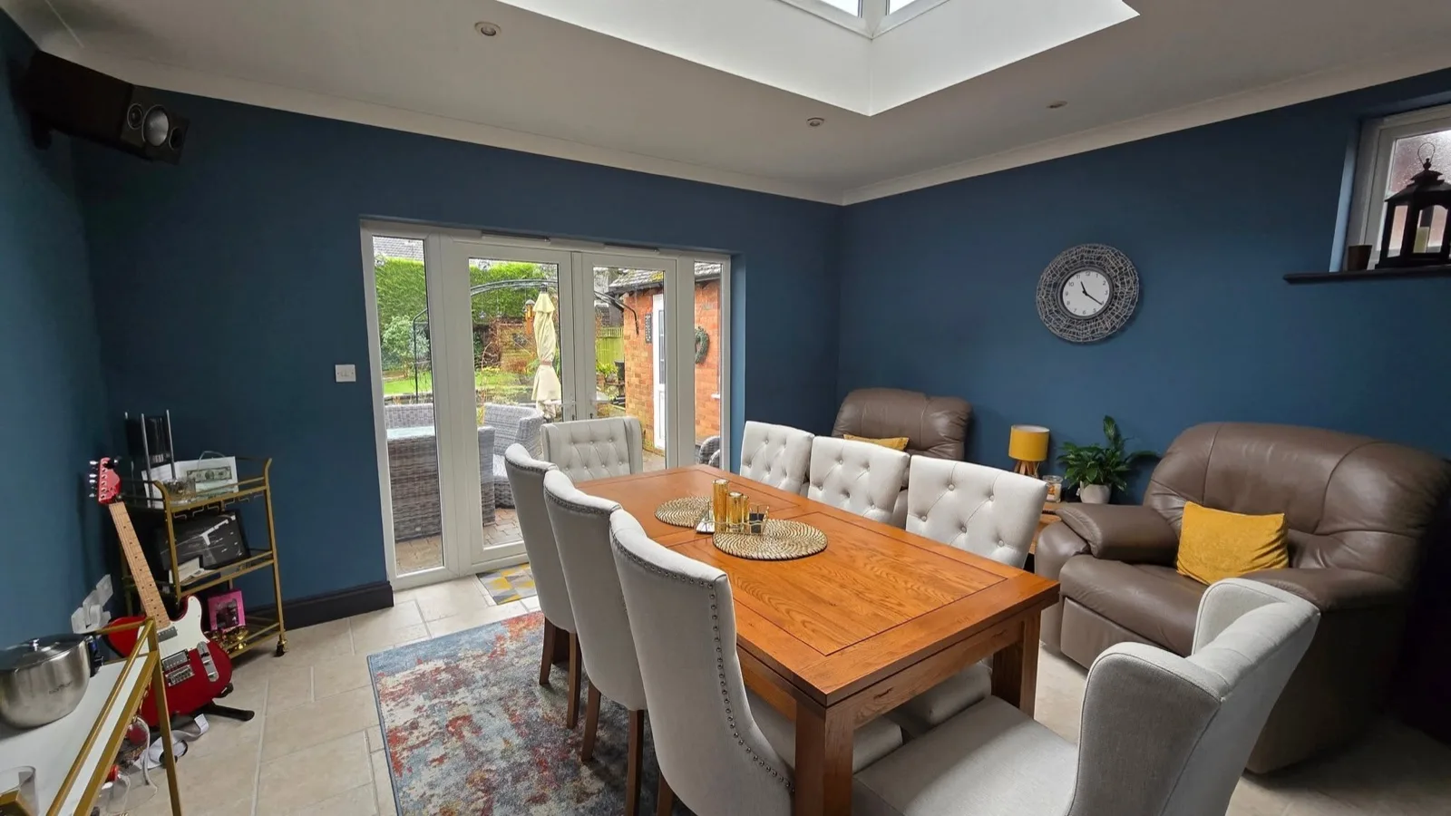 Garden room after: walls painted deep navy blue, furnished as a dining and lounge space