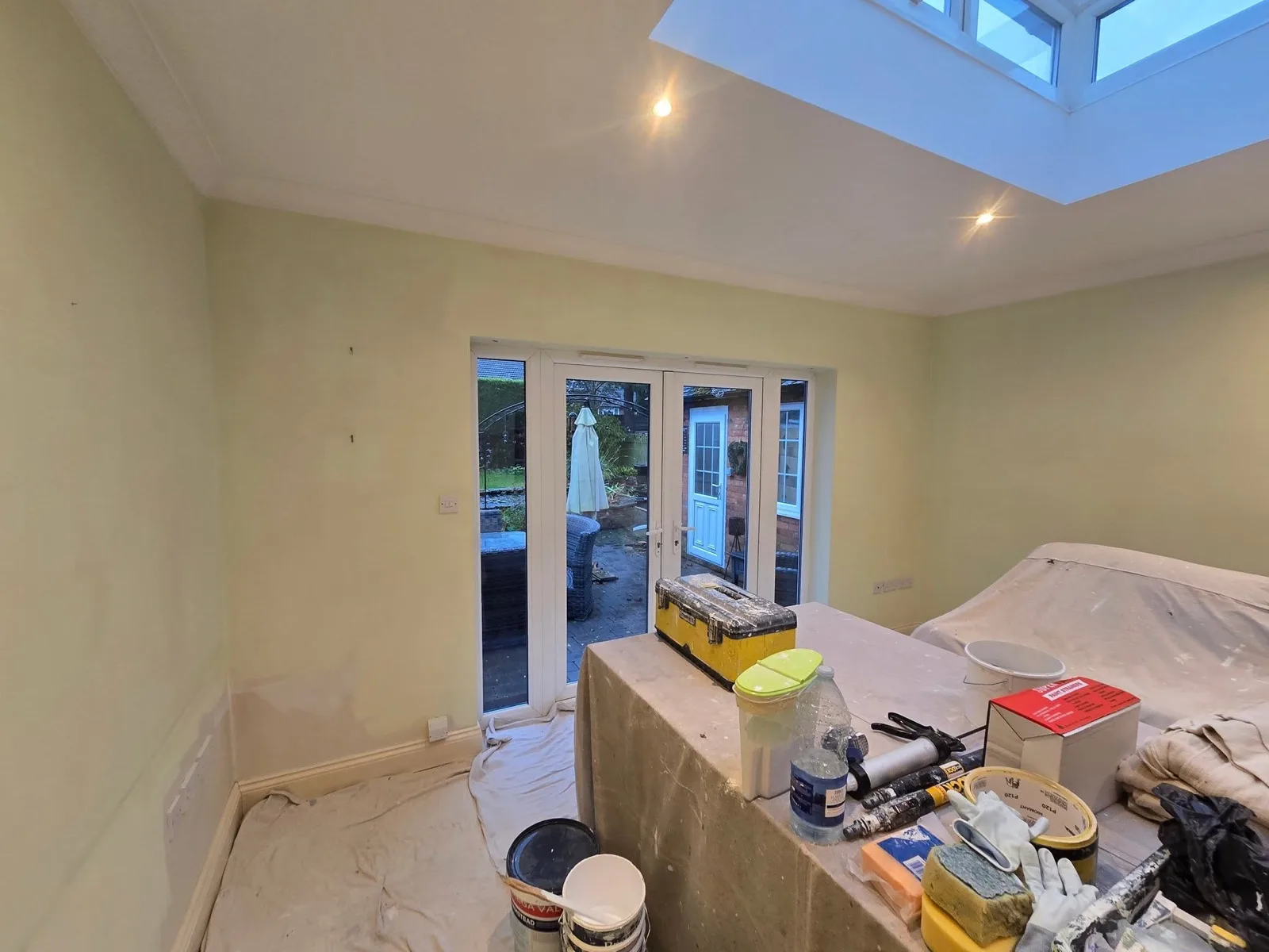 Garden room before: bare plaster walls, dust sheets and tools during preparation