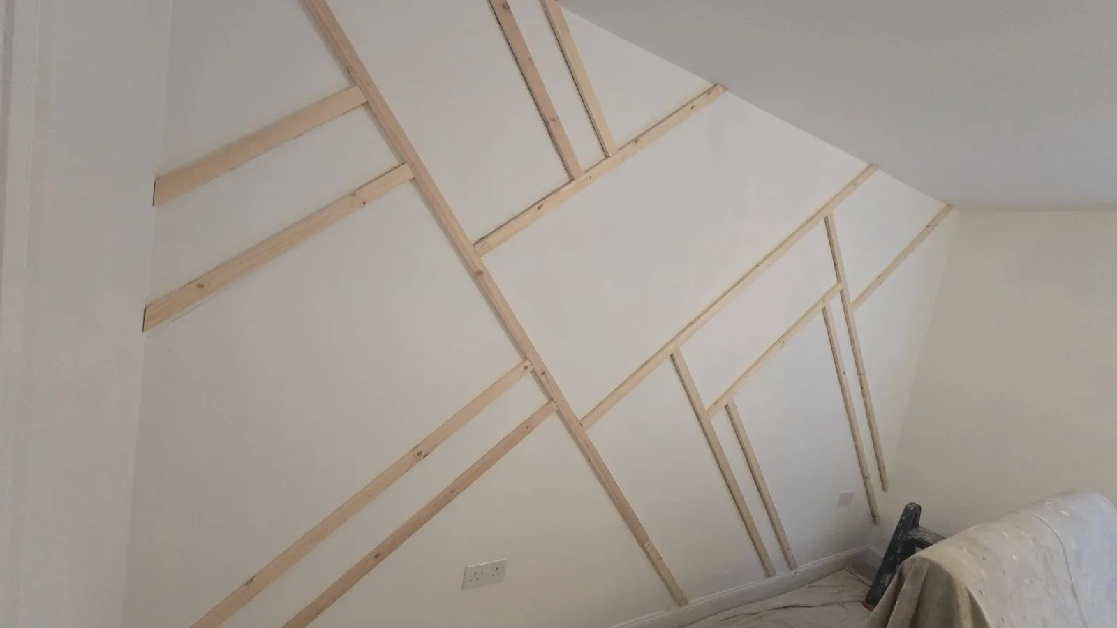 Feature wall before: raw timber battens fitted in a geometric pattern, unpainted